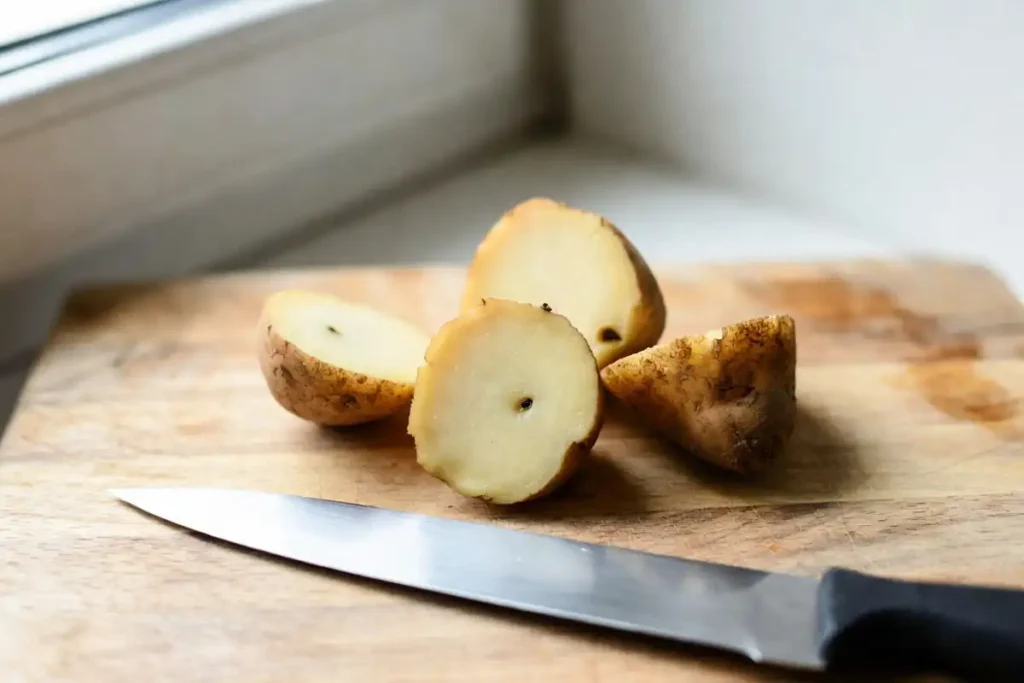 cut seed potato pieces showing healthy eyes on a wooden board before planting
