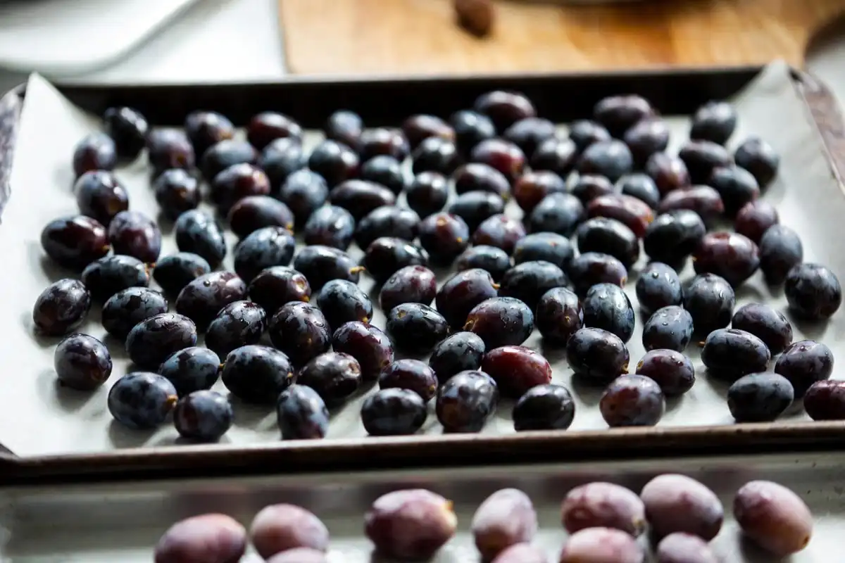 Whole muscadine grapes arranged in a single layer on a parchment lined tray ready to freeze for long term storage